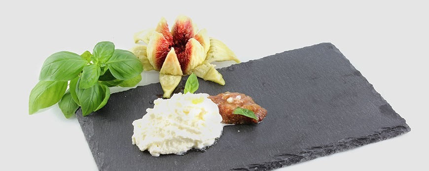 Spuma di robiola servita con fichi freschi tagliati a spicchi, foglie di basilico