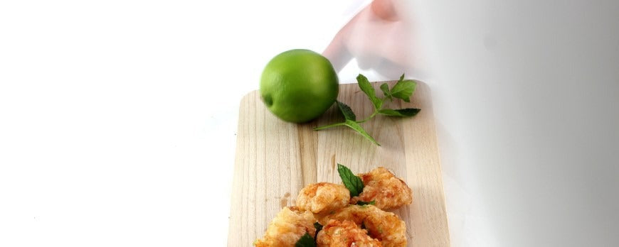 Bocconcini di pollo fritto dorati e croccanti, serviti con foglie di menta fresca e lime.