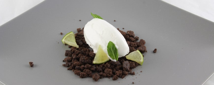 Dessert di gelato al limone fatto in casa con crumble al cioccolato, lime e foglie di mentolo.